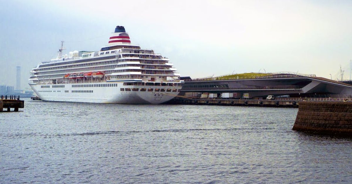 A large cruise ship docked at Yokohama port beside a modern terminal building.