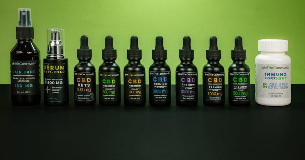 Array of CBD products including oils and serums displayed on a green backdrop.
