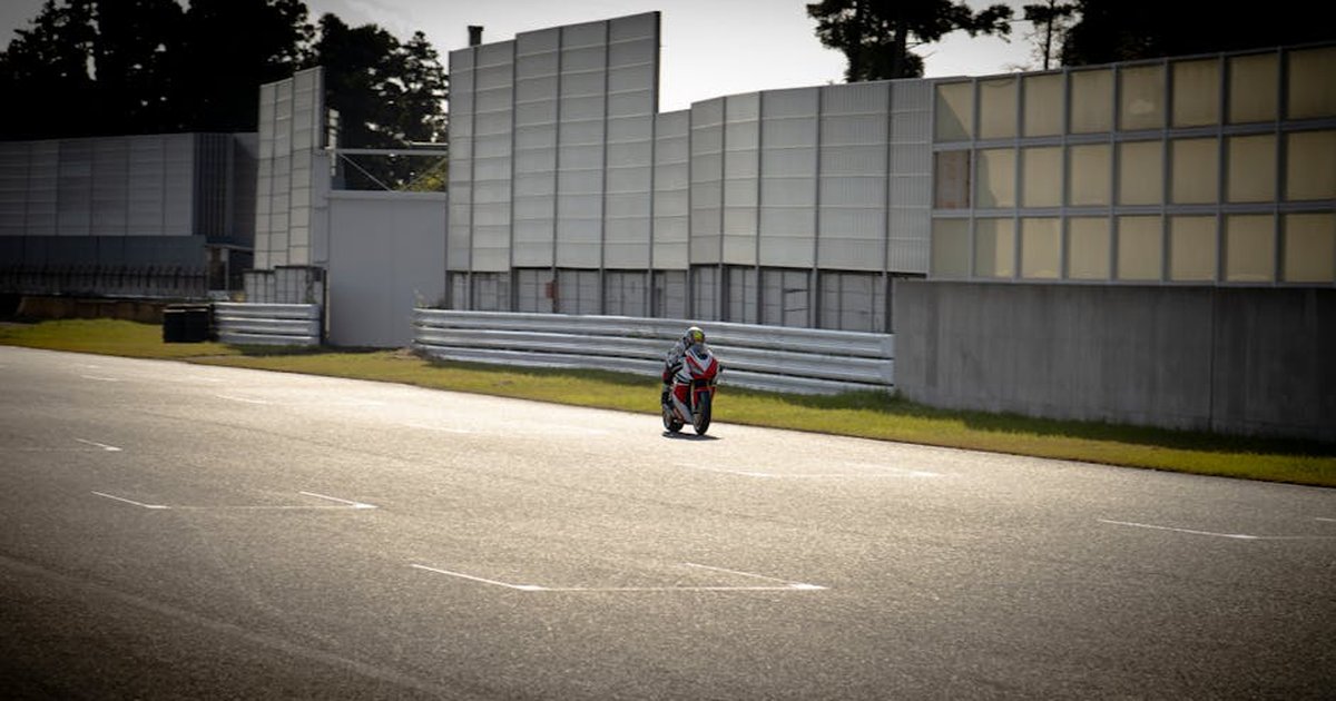 A motorcyclist speeding down a sunny racetrack, emphasizing speed and adrenaline.