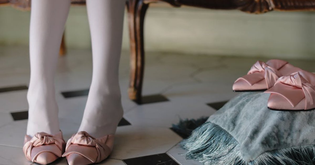 Close-up of pink satin shoes with bows, enhancing elegance in a classic interior setting.