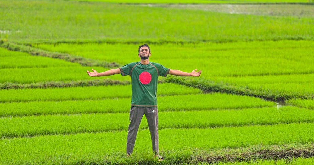 Adult male enjoying fresh air in vibrant green rice fields of Chattogram, Bangladesh.