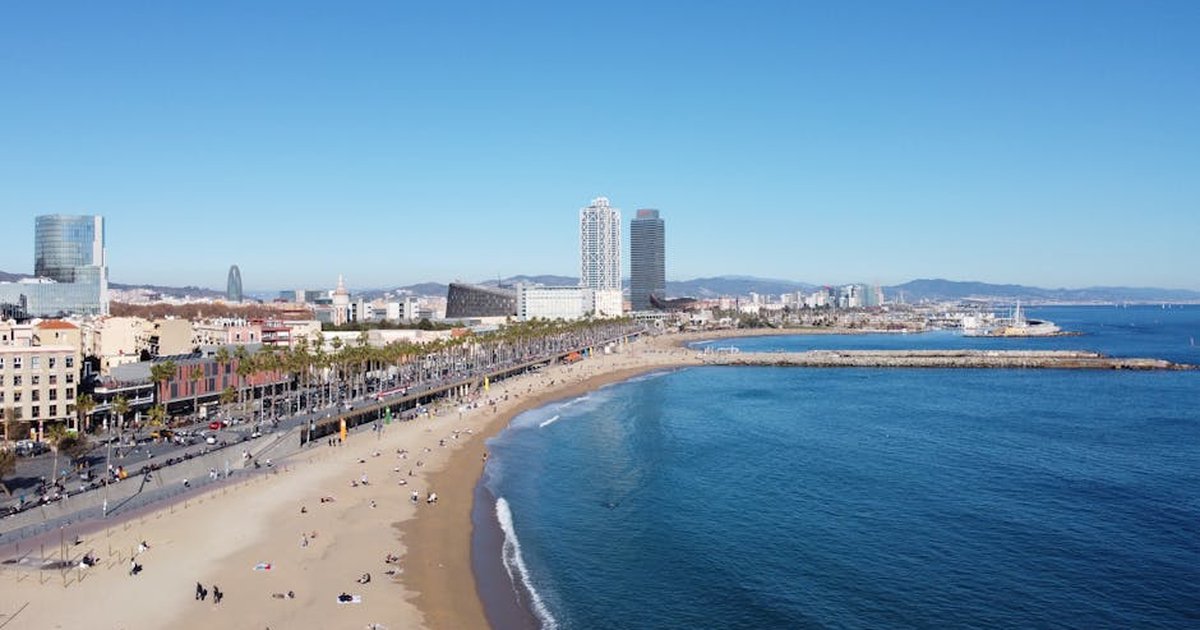 A stunning aerial shot of Barcelona's beach and city skyline on a clear day, capturing the vibrant coast.