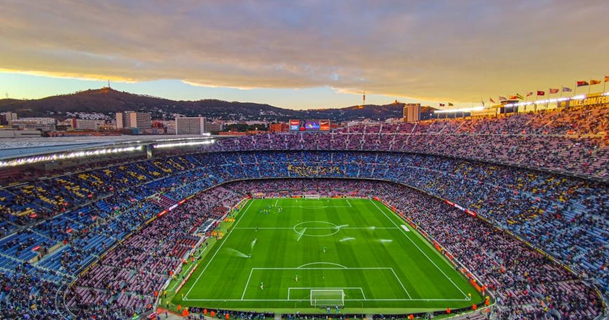 Aerial view of Camp Nou stadium filled with spectators during a football match at sunset in Barcelona, Spain.
