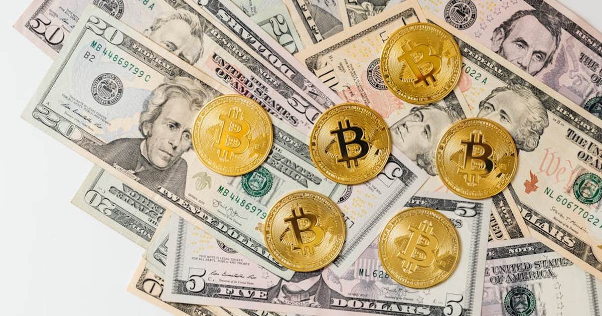 A selection of Bitcoin coins placed on US dollar bills representing cryptocurrency and traditional money.