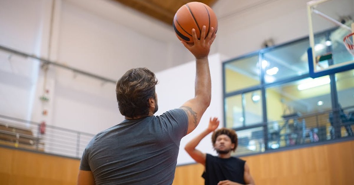 Two adult men playing an intense game of basketball indoors, capturing action and movement.