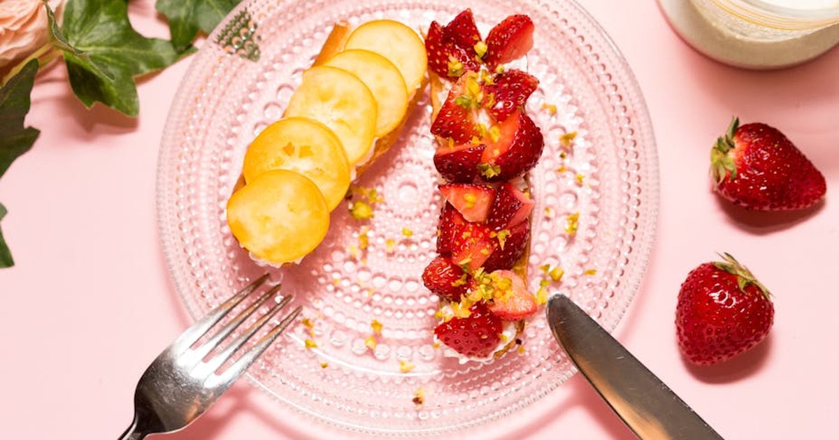 Top view of a beautifully plated dessert featuring fresh strawberries and sliced fruit on a transparent dish.