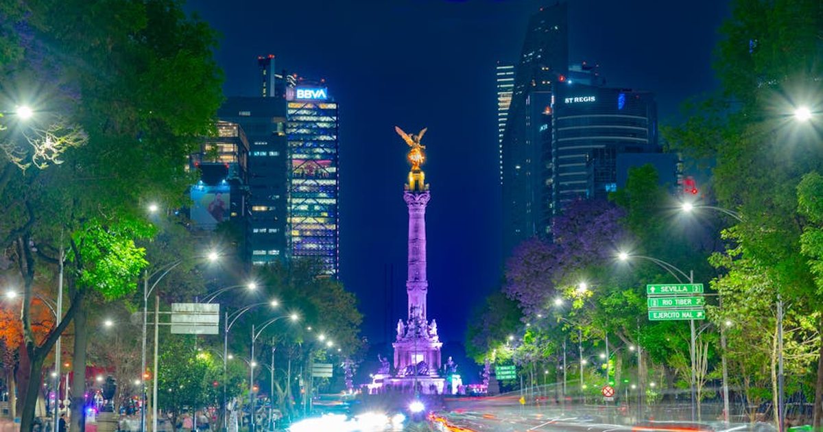 Vibrant night scene of the Angel of Independence monument in bustling Mexico City.