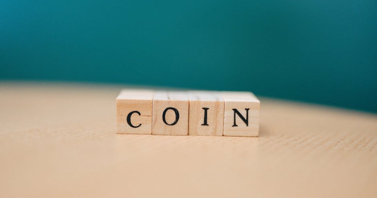 Close-up of wooden blocks spelling 'COIN' on a wooden table with a blurred background.