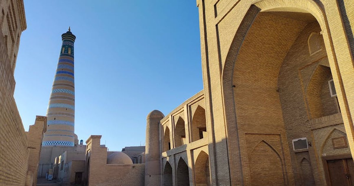 Discover the stunning architecture of Khiva with the historic Islam Khodja Minaret towering under a clear blue sky.