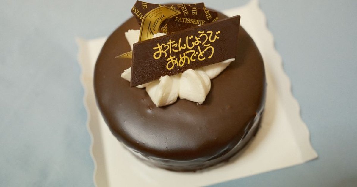 Delicious chocolate cake with creamy topping and a decorative sign in Japanese.