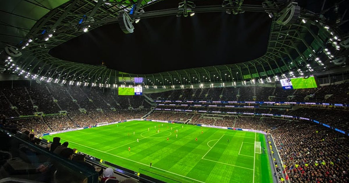 A captivating night football match at a packed stadium in England, showcasing dynamic gameplay and vibrant atmosphere.