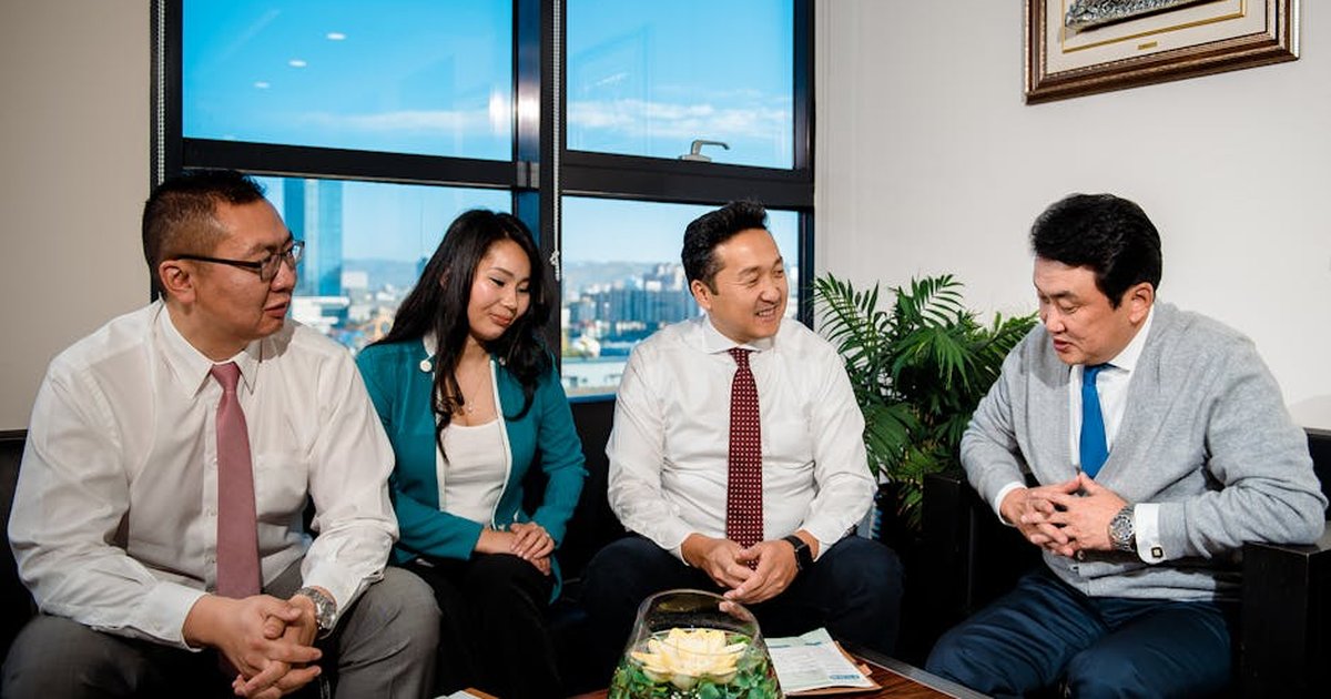 A group of business professionals engaging in a cheerful meeting in a modern office setting.