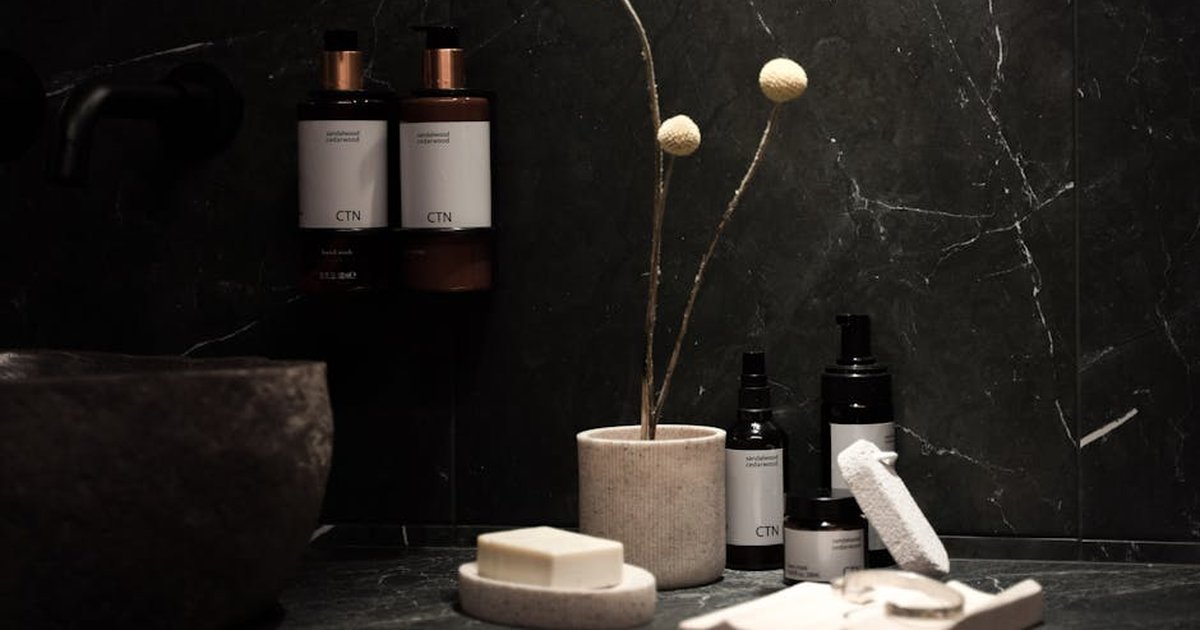 A minimalist spa scene with elegant skincare products, soap bars, and delicate decor on a dark marble countertop.