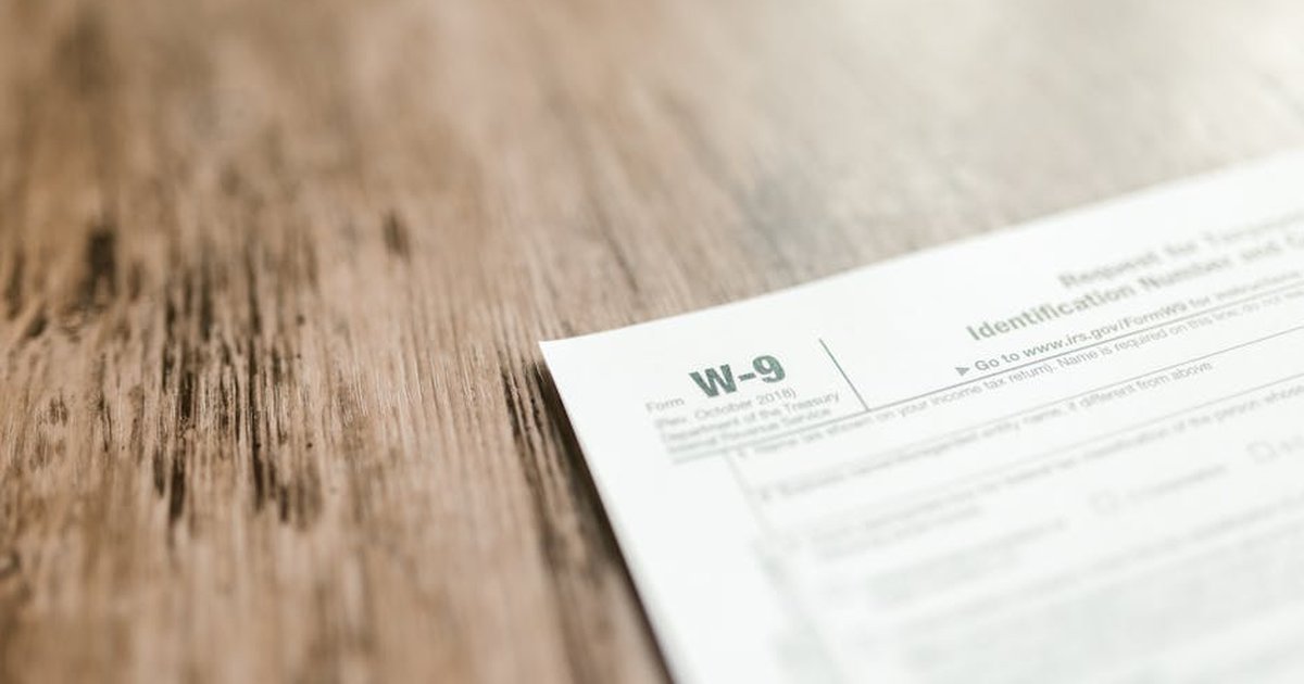 A close-up of a W-9 tax form placed on a wooden desk, emphasizing paperwork and finance.