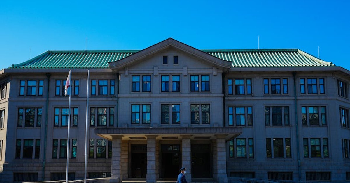 An architectural view of a government building with a person walking past under a clear blue sky.