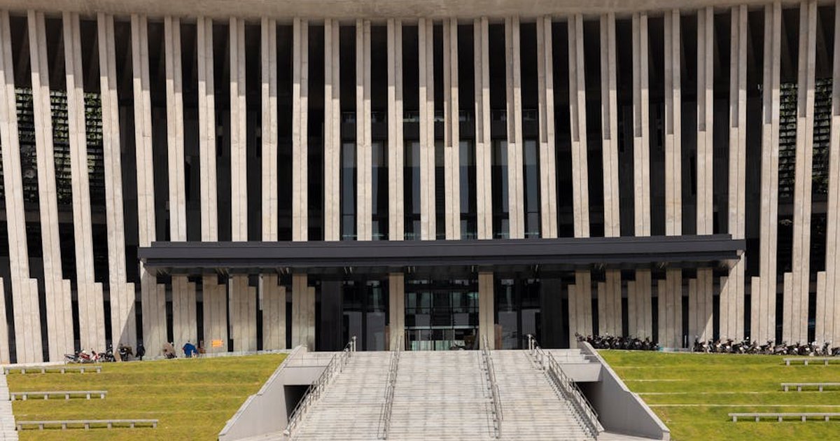 Dramatic facade of a modern architectural building with vertical columns and entrance stairs.