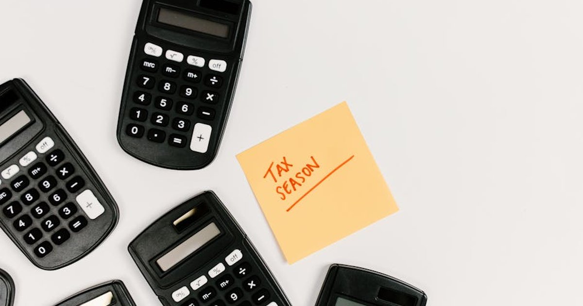 Top view of calculators with a tax season sticky note on a white background.