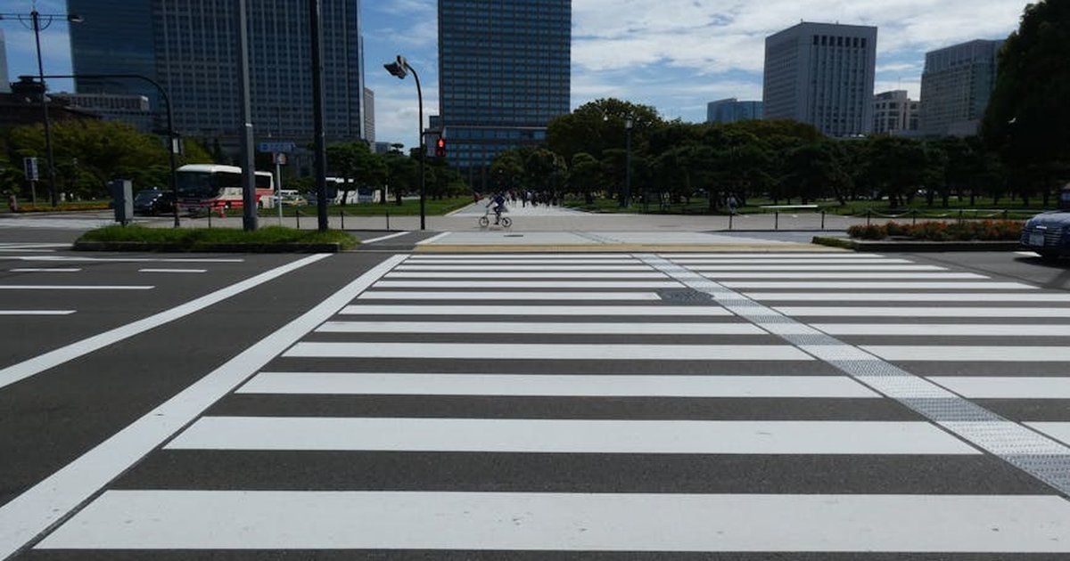 Broad zebra crossing in Tokyo with modern skyscrapers in the background, depicting urban life.