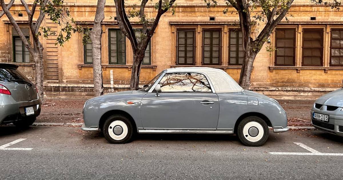A classic vintage convertible parked on an urban street in Valletta, Malta, showcasing retro charm against a historic building.