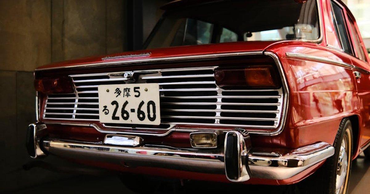 A classic vintage red car with a retro design, photographed in London showcasing its unique tail lights and license plate.