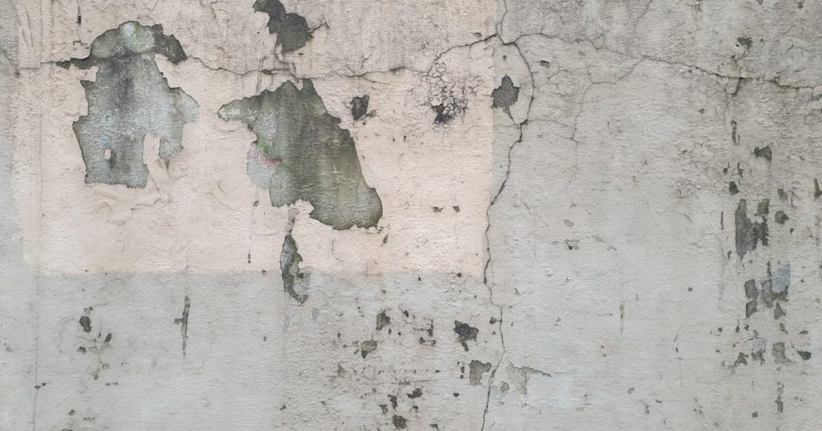 Close-up of a weathered wall showing peeling paint and cracked textures, ideal for backgrounds.