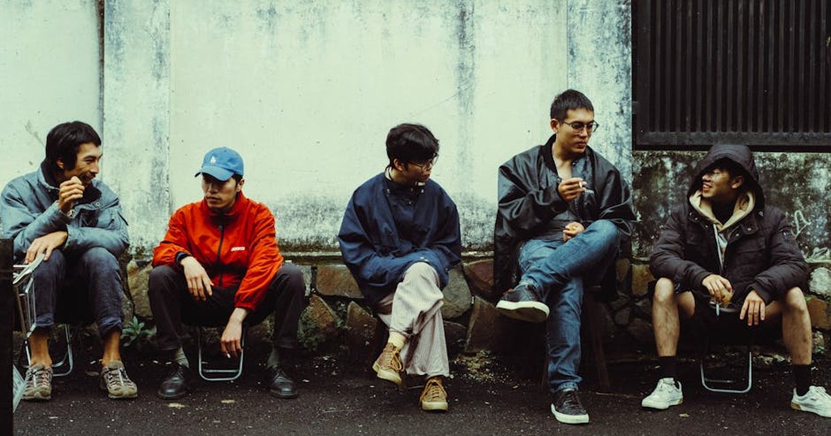 Group of friends sitting and chatting casually on a street bench during the day.