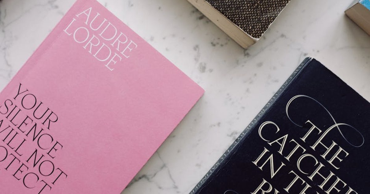 Top view of famous novels with stylish covers placed in row on white marble background