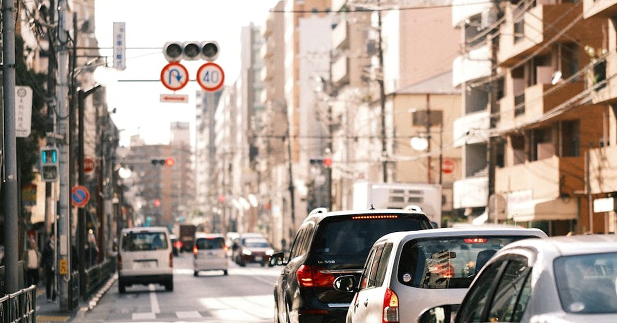 Bustling Tokyo street with cars in daytime traffic under urban cityscape and clear sky.