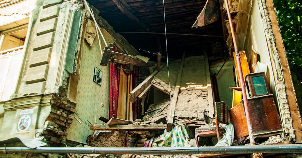 Exterior view of a damaged building with the interior exposed, showcasing severe structural collapse.