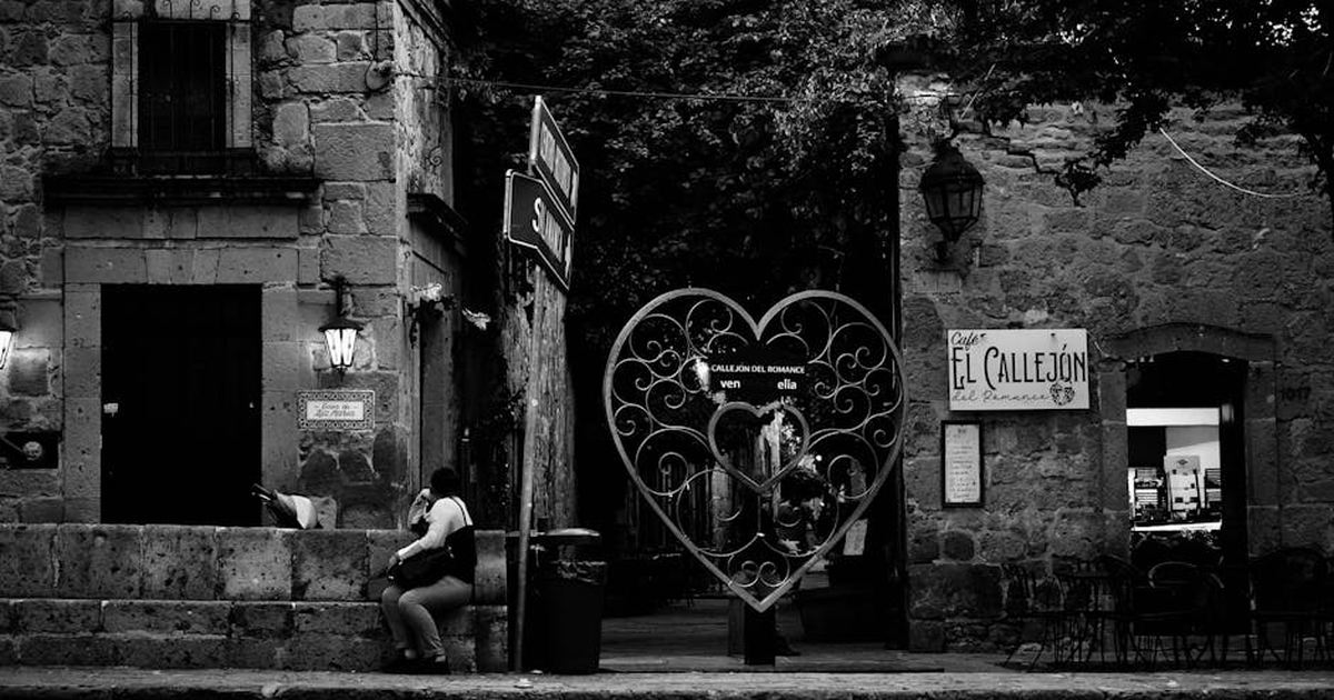 Black and white view of Callejón del Romance in Morelia with heart-shaped gate and street scene.