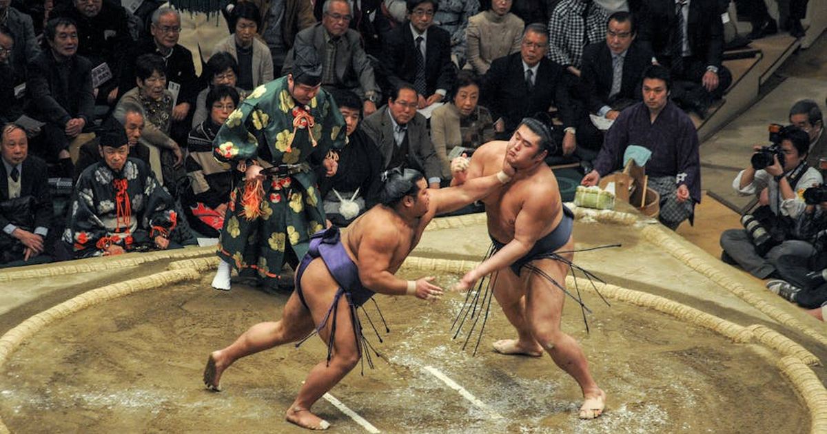 Sumo wrestlers compete in a traditional match with an enthusiastic audience in Japan.