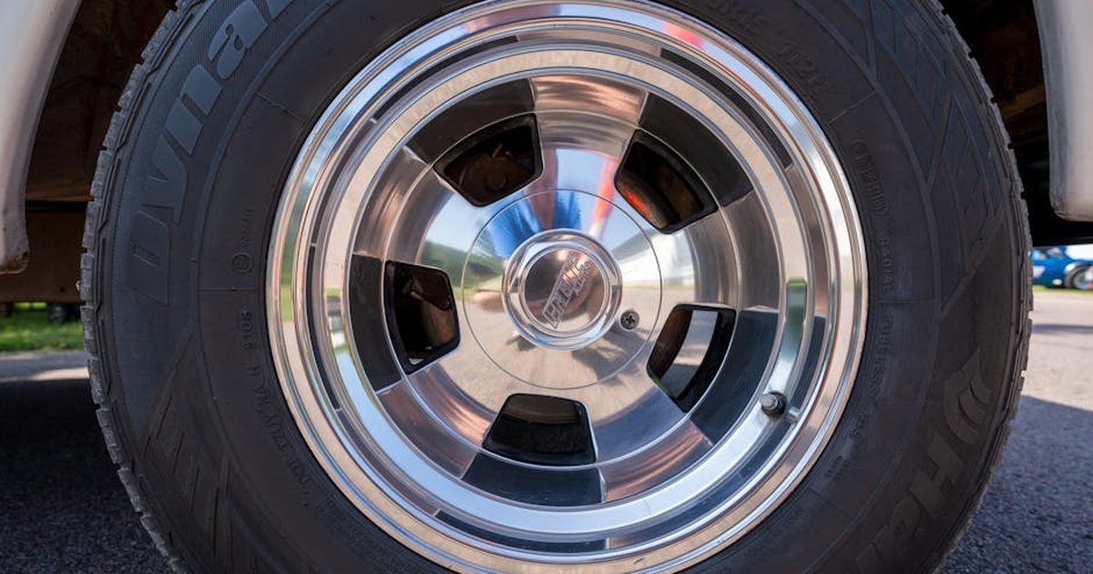 A detailed view of a polished car wheel rim and tire in bright daylight.