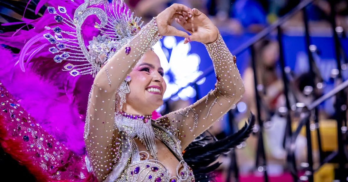 A dancer in colorful costume performs at the Encarnación carnival in Paraguay, showcasing vibrant feathers and intricate designs.