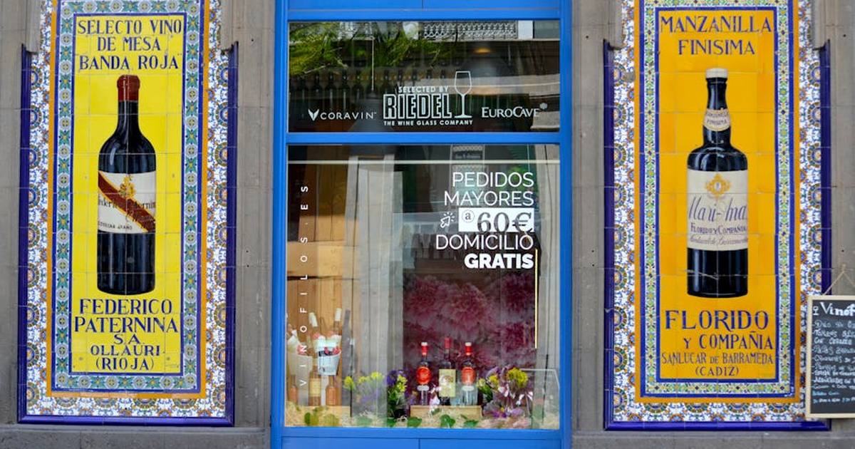Vibrant shopfront in Cadiz with decorative wine posters and blue entrance.