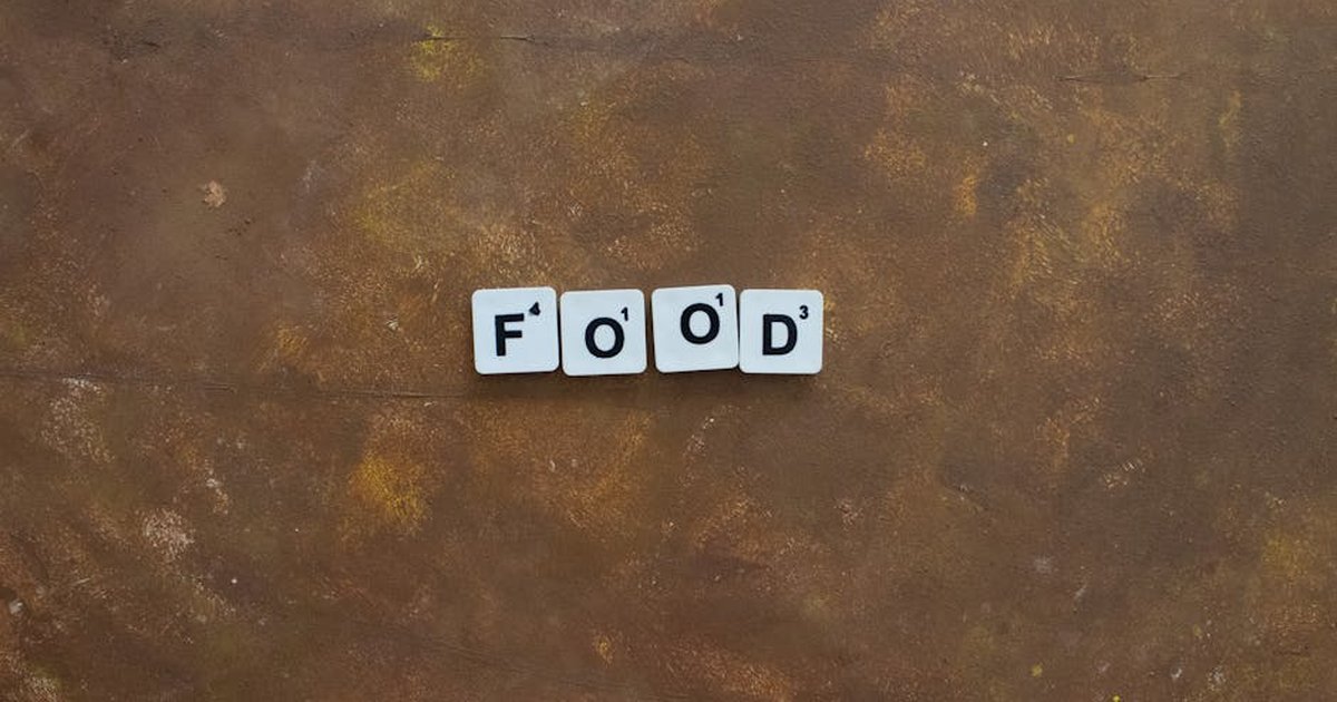 Scrabble tiles spelling 'Food' on a textured brown surface, ideal for culinary and game-related themes.