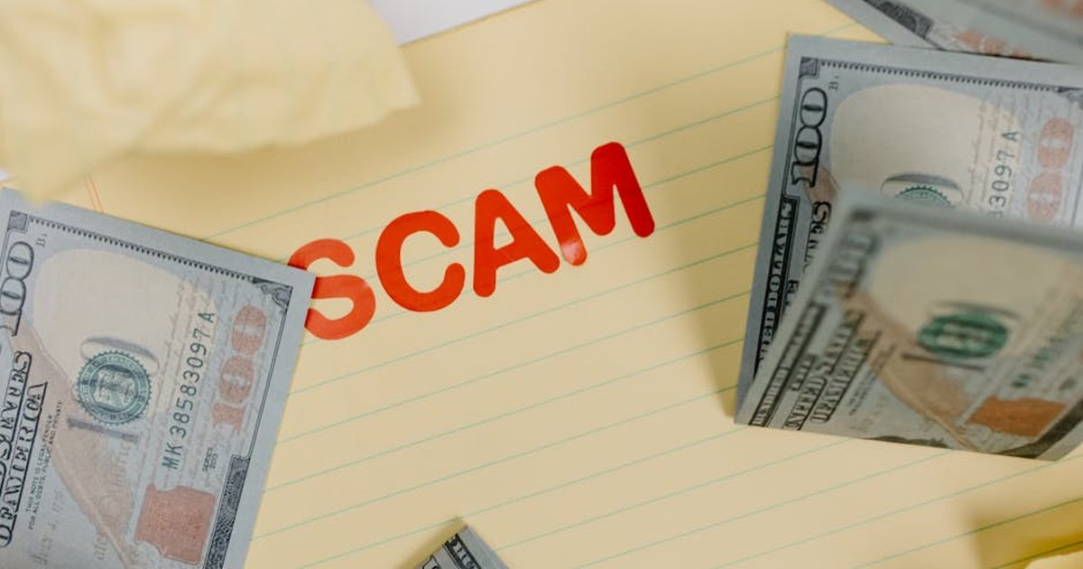Conceptual image of financial scam with US dollars on yellow paper and word 'scam' visible.