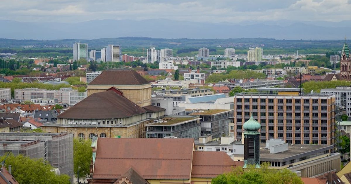 Scenic aerial view of Freiburg showcasing historic and modern architecture under a cloudy sky.