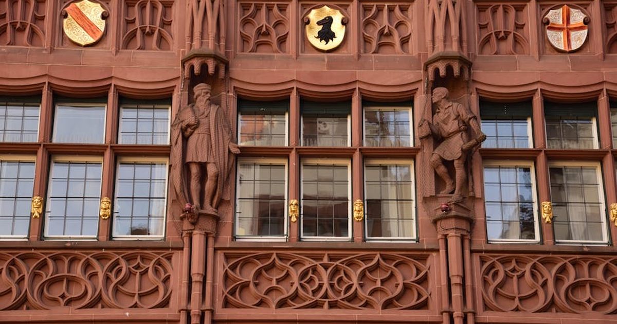 Ornate facade of historic building in Freiburg, featuring intricate stone carvings and emblems.