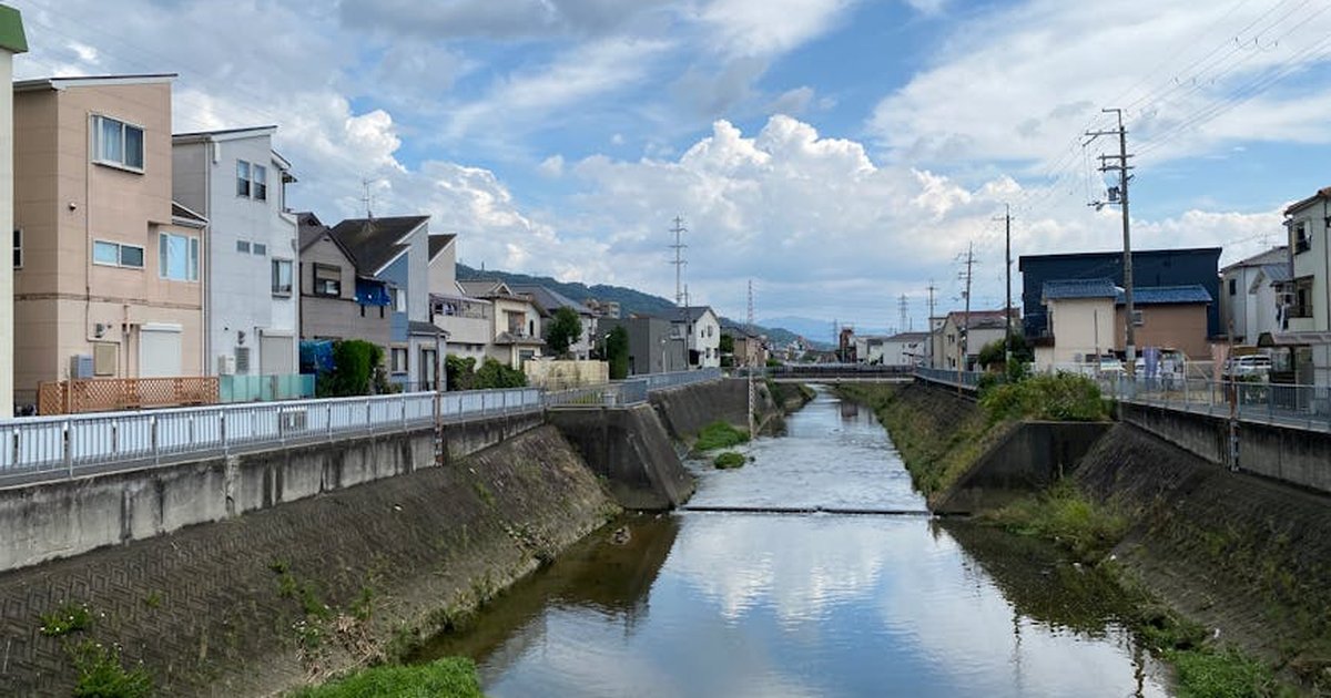 Charming urban canal reflecting houses and clouds under a clear sky.