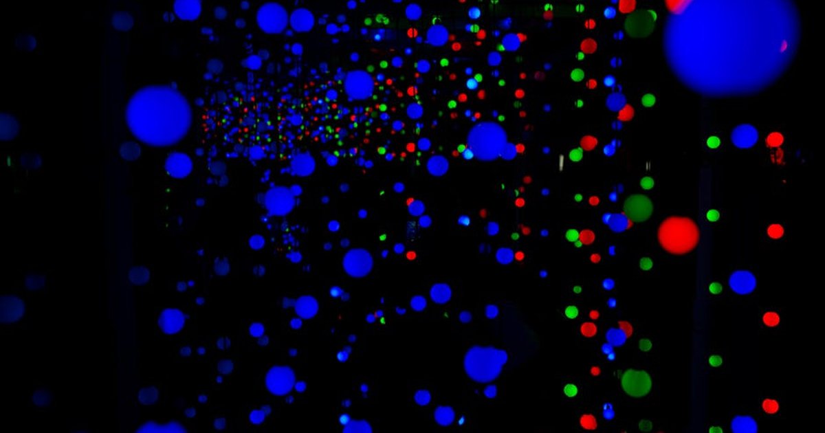 Abstract display of vivid blue, red, and green light spheres in dark space.