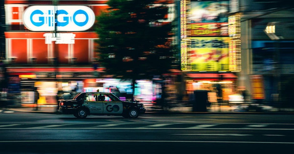 A bustling urban night scene featuring a speeding taxi in a vibrant city street.