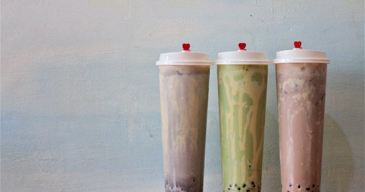 Elegant presentation of three bubble tea flavors in sealed tall cups with red heart lids.