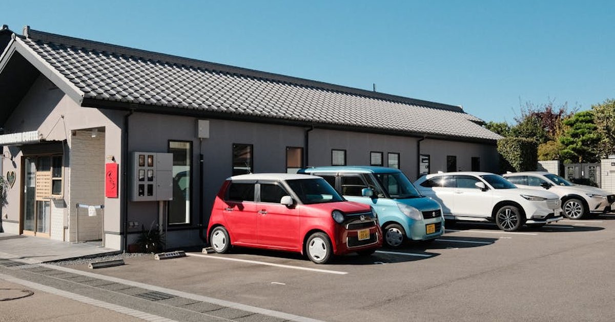 A charming coffee shop with parked cars under a clear blue sky in Inuyama, Japan.