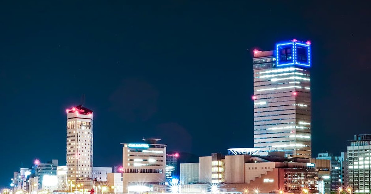 A vibrant night view of Takamatsu's cityscape in Kagawa, Japan, showcasing illuminated skyscrapers along the waterfront.