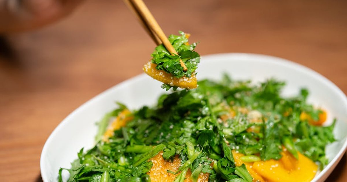Delicious Asian salad garnished with fresh greens and chopsticks, showcasing vibrant colors and textures.