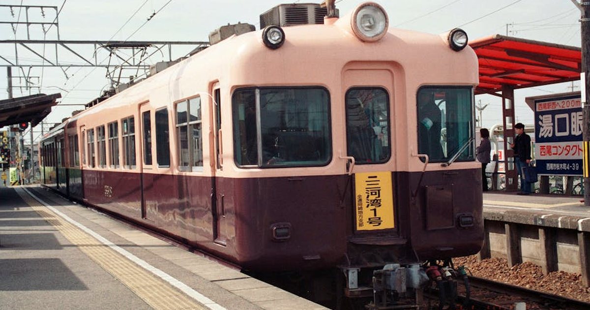 A vintage train at a Japanese station platform on a clear day.