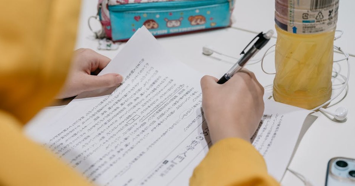Close-up of individual studying Japanese text with colorful stationery on desk.