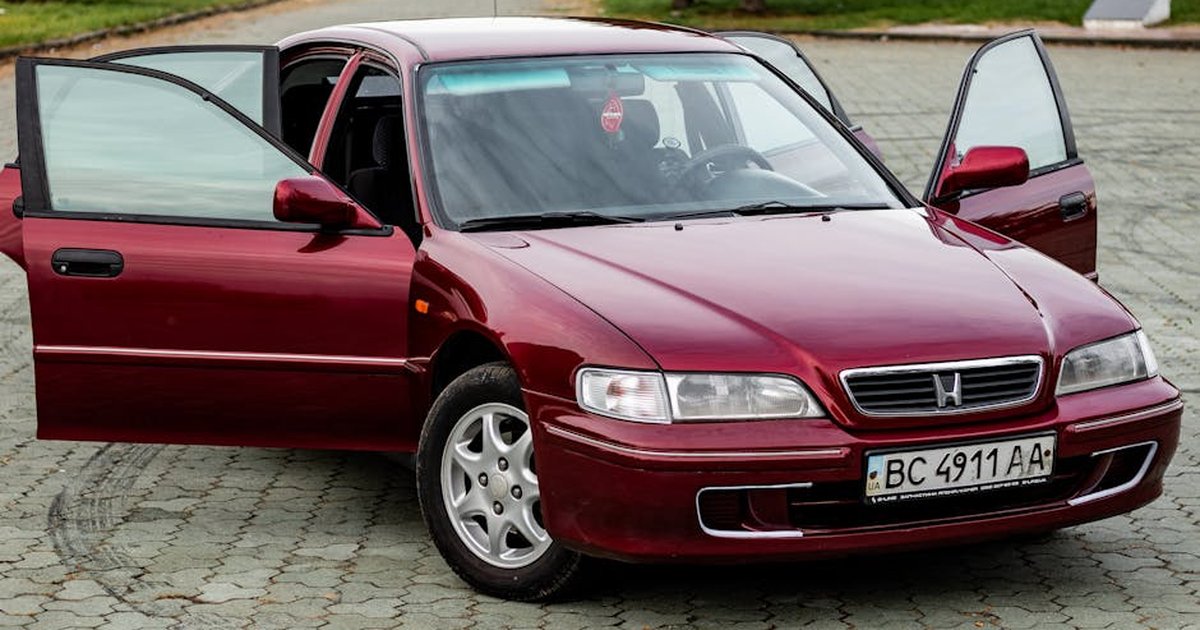 Red Honda sedan parked outdoors with doors open, ideal for automotive themes.