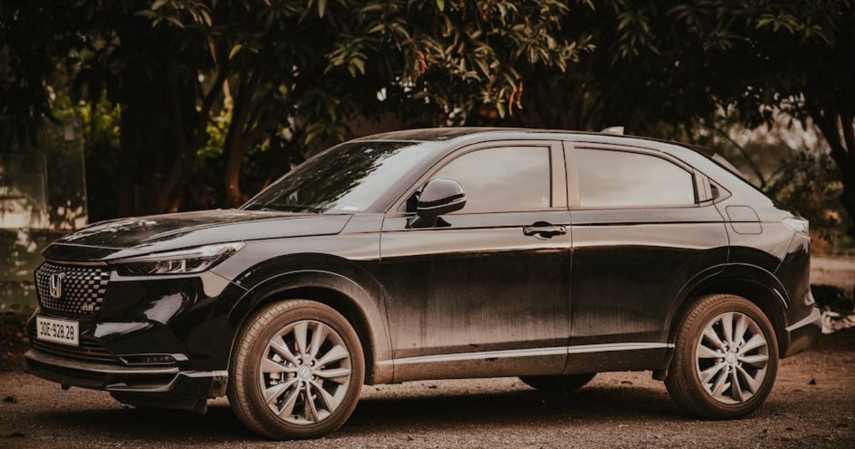 A stylish black Honda HR-V SUV parked outdoors amongst trees on a sunny day.