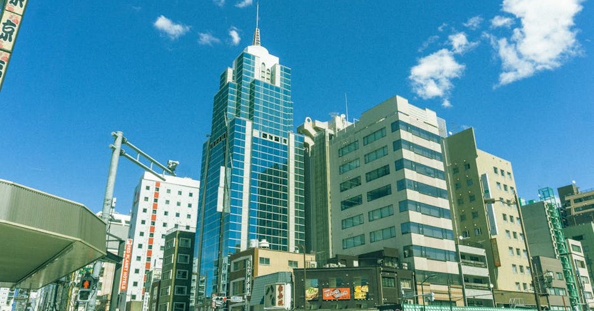 Vibrant Tokyo street scene showcasing modern skyscrapers under a bright blue sky.